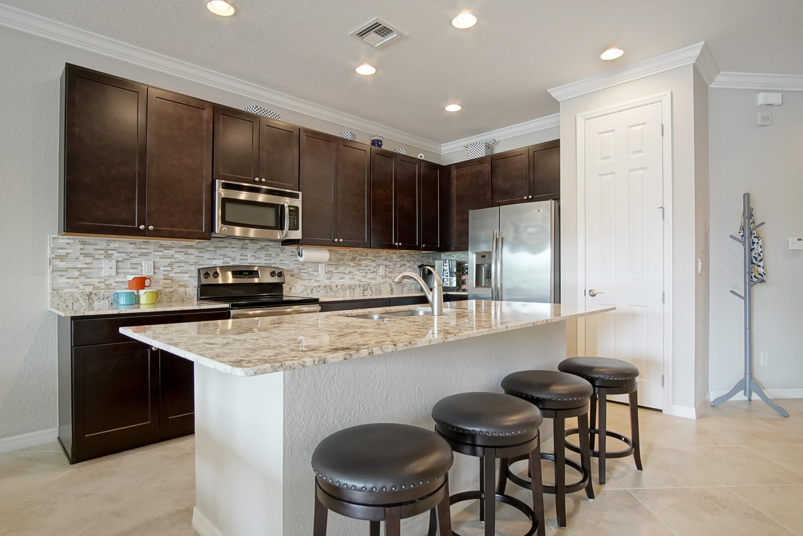 638 Southwest Glen Crest Way Stuart, FL 34997 - Photo 6 of 32 a kitchen with stainless steel appliances granite countertop a table chairs sink refrigerator and microwave