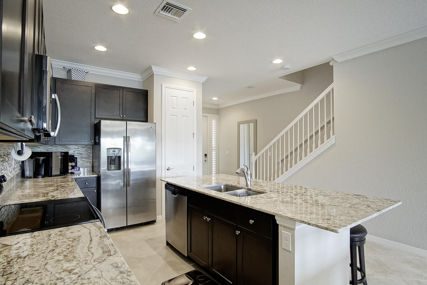 638 Southwest Glen Crest Way Stuart, FL 34997 - Photo 7 of 32 a kitchen with stainless steel appliances kitchen island granite countertop a refrigerator a sink and a stove