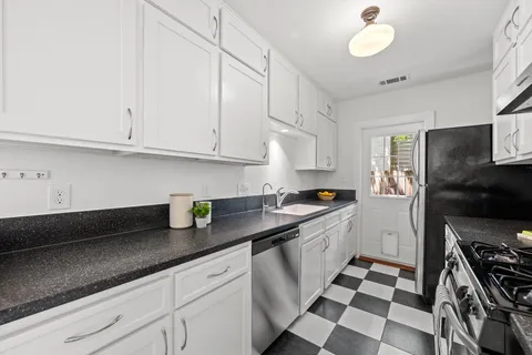 a kitchen with granite countertop stainless steel appliances a sink a stove and a refrigerator