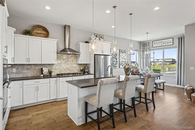 a kitchen with stainless steel appliances kitchen island granite countertop a table chairs and a refrigerator