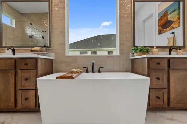 a view of bathroom with a tub double sink mirror and
