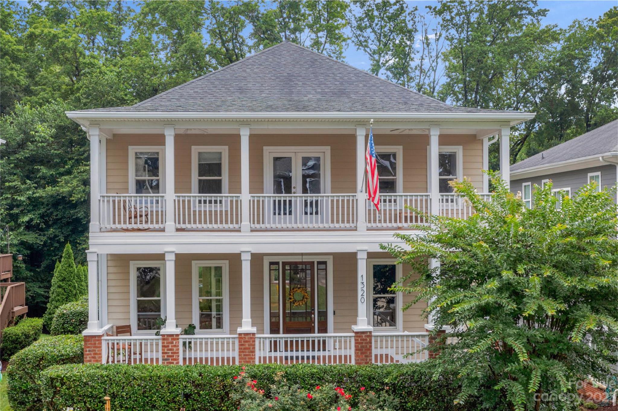 a view of a white house with large windows and a large tree