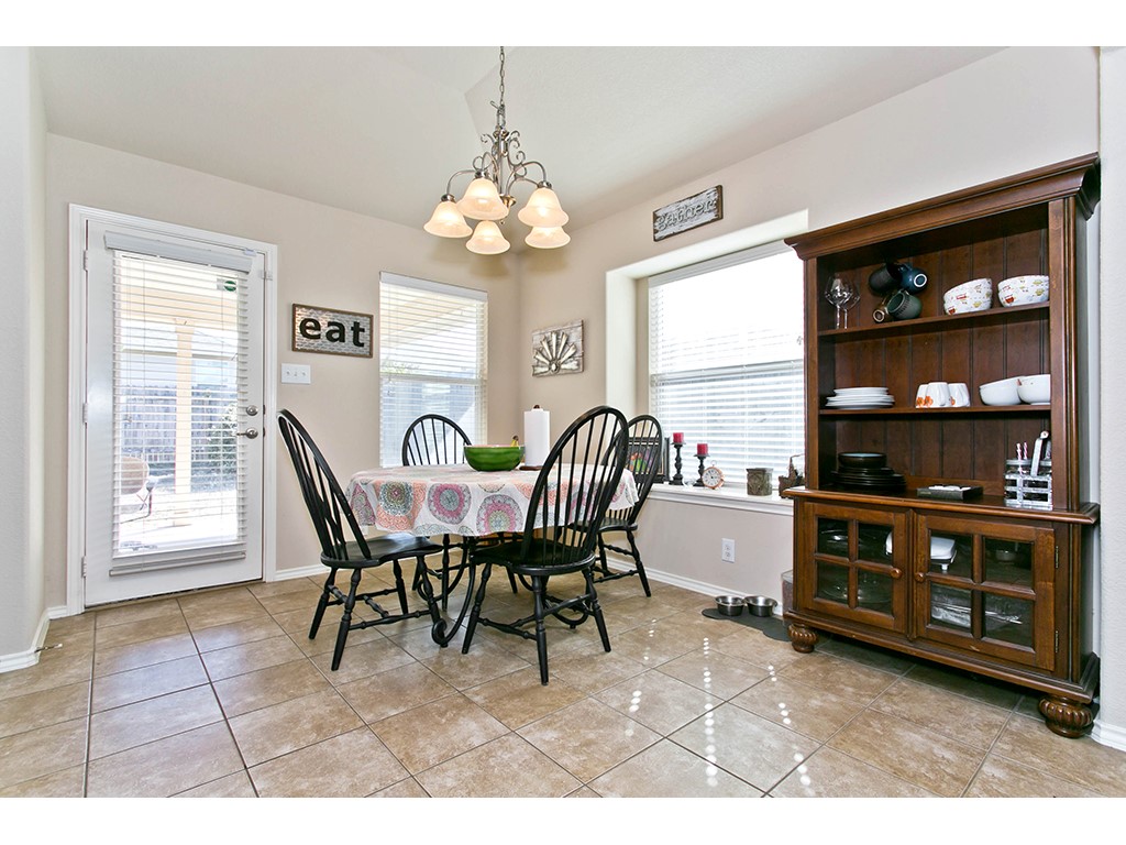 1808 Sand Creek Road Cedar Park, TX 78613 - Photo 8 of 25 Dining area featuring ceramic tile flooring, a multi-light chandelier, a window with horizontal blinds, and a glass-paneled exterior door