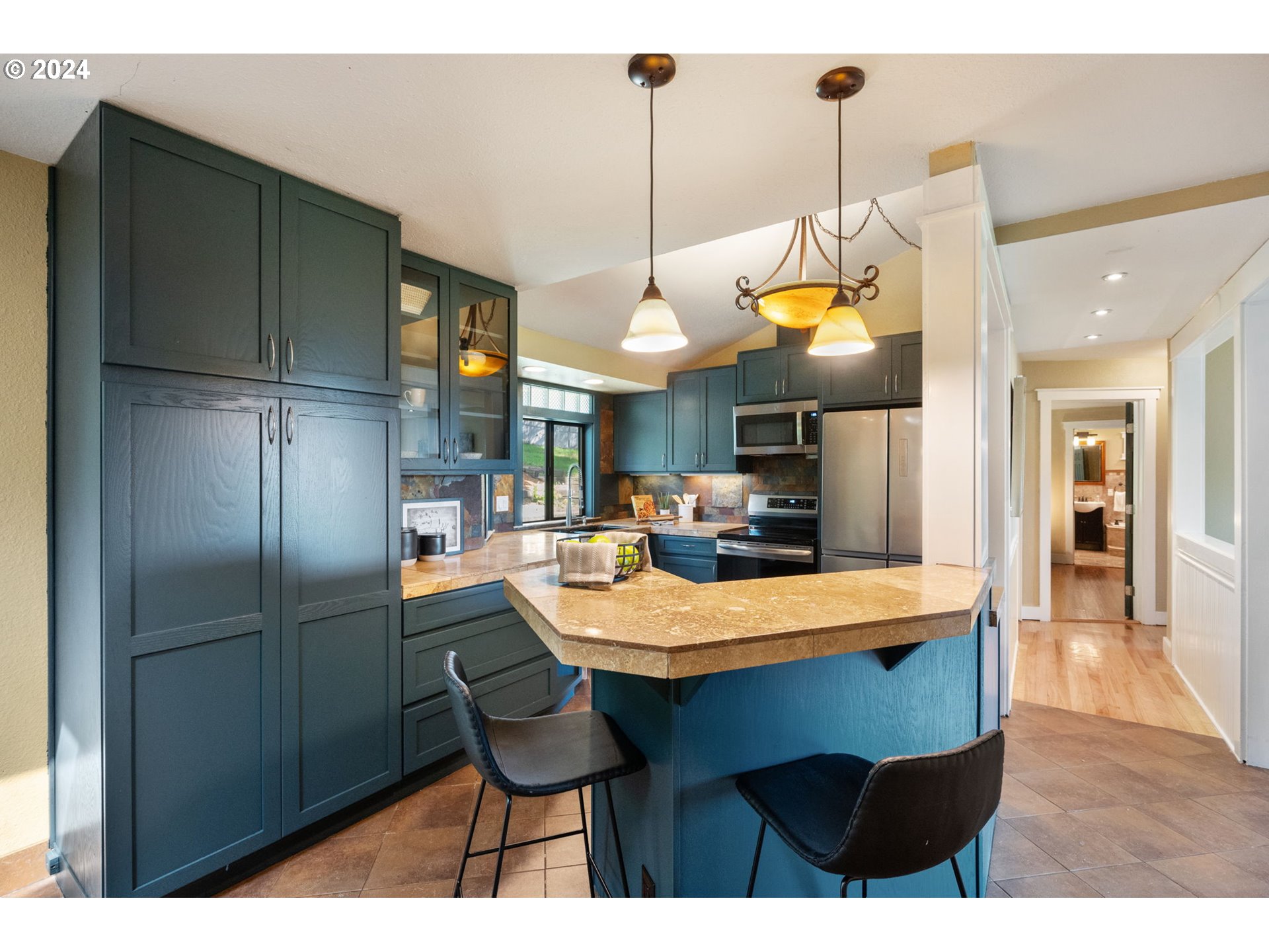 8511 Southeast Barbara Welch Road Portland, OR 97236 - Photo 5 of 30 a kitchen with stainless steel appliances kitchen island granite countertop a refrigerator a microwave oven a sink with a dining table and chairs