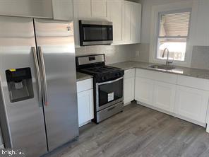 5822 Saul Street Philadelphia, PA 19149 - Photo 3 of 15 a kitchen with stainless steel appliances granite countertop a refrigerator a stove a sink and a microwave