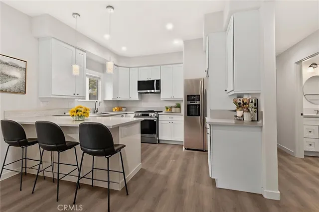 a kitchen with granite countertop a refrigerator cabinets and chairs
