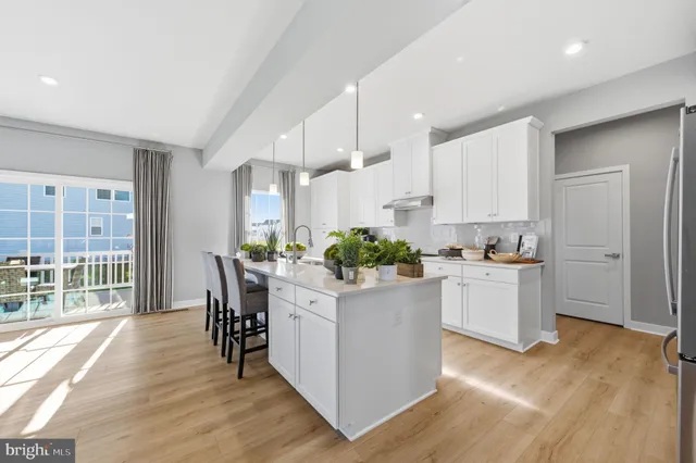 a kitchen with white cabinets and wooden floor