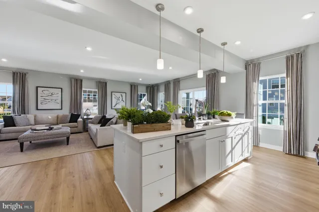 a large kitchen with kitchen island a white cabinets a sink a window and wooden floors