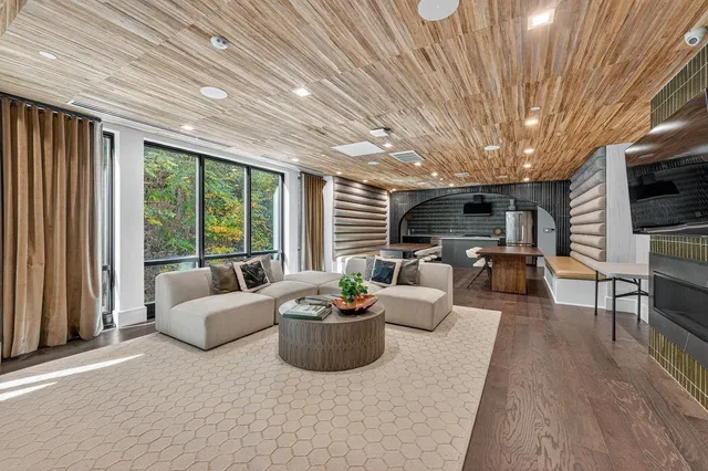 a living room with furniture a flat screen tv and large windows