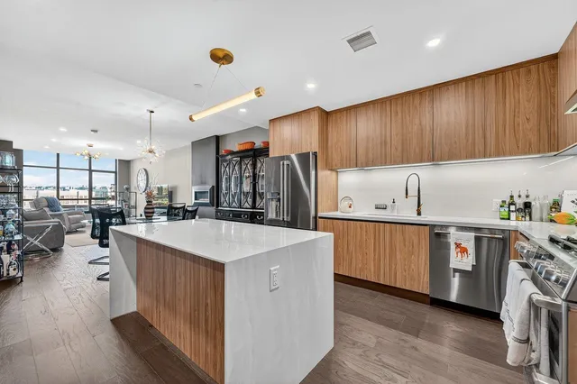 a kitchen with kitchen island granite countertop wooden floors a stove a sink and a center island
