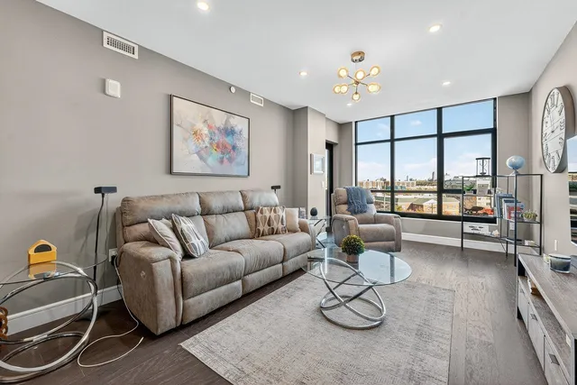 a living room with furniture a chandelier and a floor to ceiling window