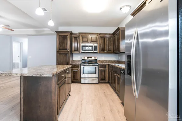 a kitchen with stainless steel appliances granite countertop a stove a sink and a refrigerator