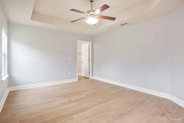 a view of an empty room with window and a chandelier fan