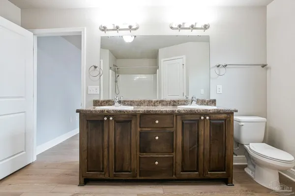 a bathroom with a granite countertop toilet a sink and a mirror
