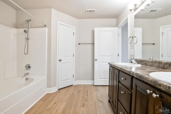 a bathroom with a granite countertop sink a mirror a bathtub and shower
