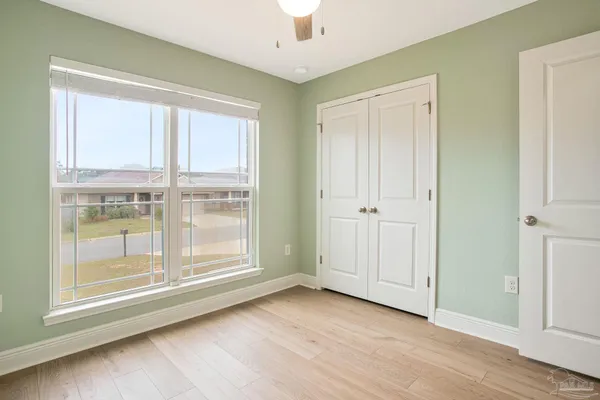 an empty room with wooden floor cabinet and windows