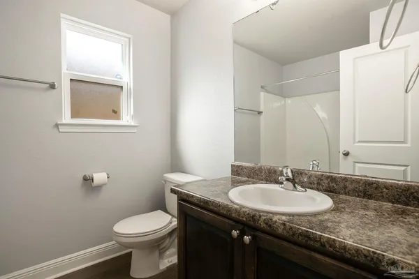 a bathroom with a granite countertop sink and a toilet