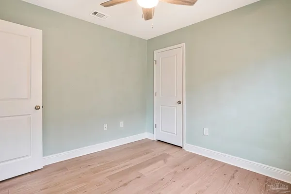 an empty room with a ceiling fan and wooden floor