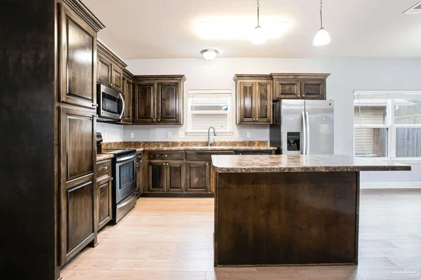a kitchen with stainless steel appliances granite countertop a stove a sink and a refrigerator