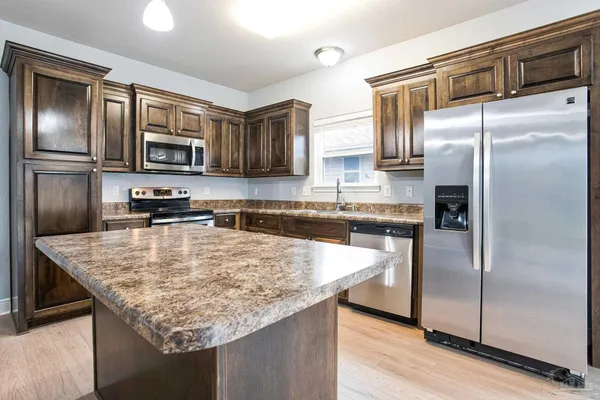 a kitchen with stainless steel appliances granite countertop a refrigerator a stove and a sink