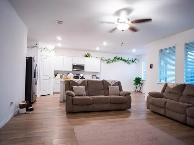 a living room with furniture kitchen view and a chandelier