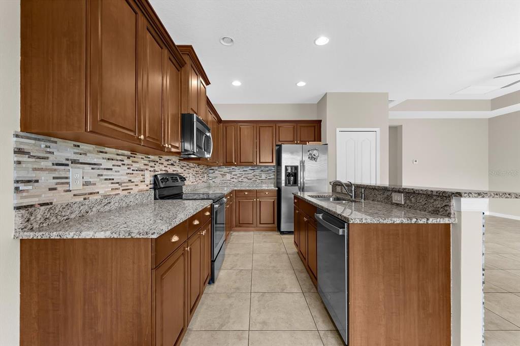 4326 Forest Creek Trail Parrish, FL 34219 - Photo 14 of 73 a kitchen with stainless steel appliances granite countertop wooden cabinets a stove top oven a sink and dishwasher
