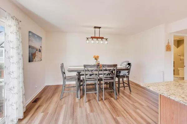 a kitchen with kitchen island a stove a chandelier a dining table and chairs