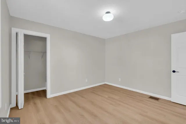 a view of an empty room with wooden floor and closet