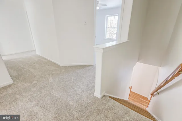 an empty room with windows and chandelier fan
