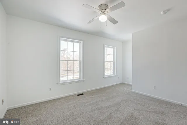 an empty room with windows and ceiling fan