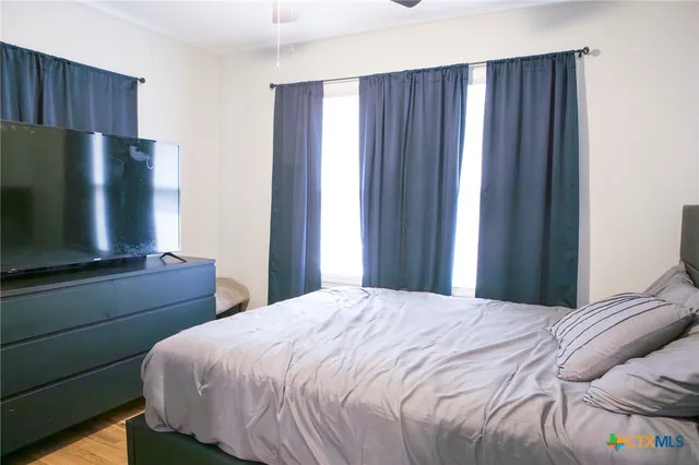 a bedroom with a bed tv and a refrigerator