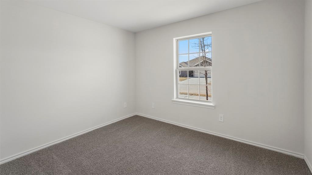 1969 Freeman Street Tyler, TX 75704 - Photo 17 of 30 Bright interior room featuring a grid-pattern window, light gray walls, dark gray carpet, and white baseboards