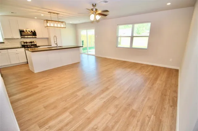 a kitchen with granite countertop a stove a sink and white cabinets with wooden floor