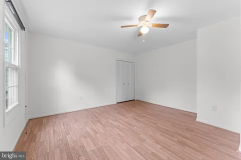 a view of empty room with wooden floor and fan