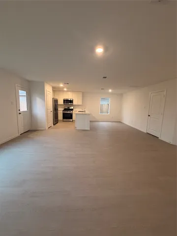 a view of an empty room with a fireplace and window