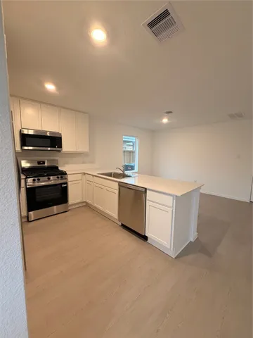 a kitchen with stainless steel appliances a stove top oven and white cabinets