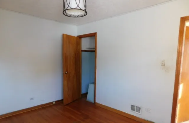 an empty room with wooden floor and window