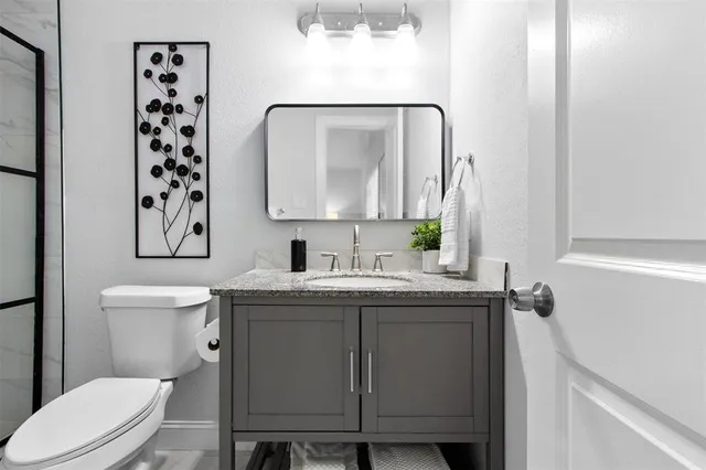 a bathroom with a granite countertop toilet sink and mirror