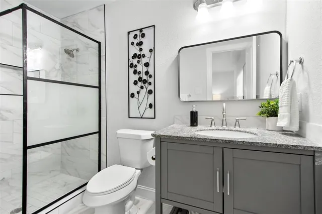 a bathroom with a granite countertop sink toilet and shower