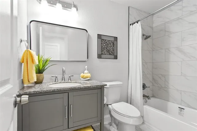 a bathroom with a granite countertop sink mirror vanity and toilet