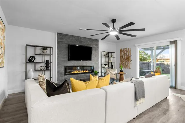 a living room with furniture a ceiling fan and a flat screen tv