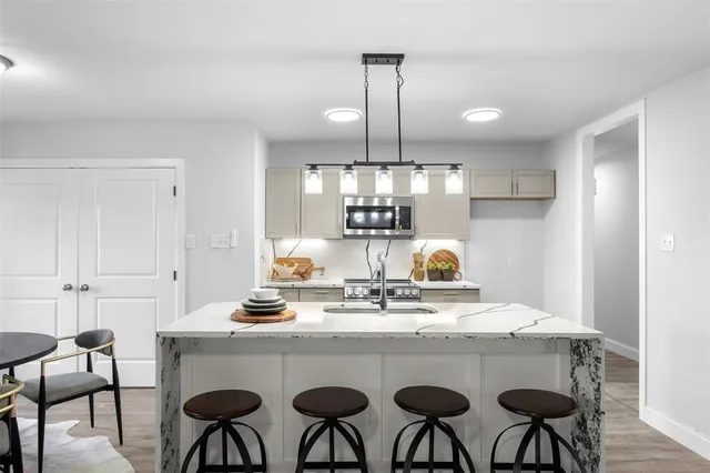 a kitchen with stainless steel appliances granite countertop a table chairs stove and white cabinets