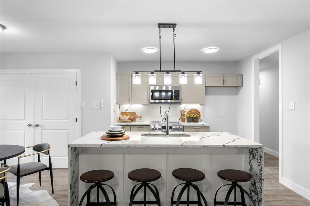 5405 Ramsey Drive The Colony, TX 75056 - Photo 9 of 32 a kitchen with stainless steel appliances granite countertop a table chairs stove and white cabinets