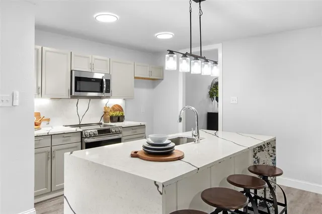 a kitchen with stainless steel appliances a dining table chairs and white cabinets