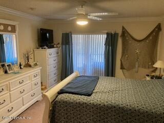 201 25th Avenue South, Unit N32 Jacksonville Beach, FL 32250 - Photo 13 of 38 a bedroom with a bed a mirror on dresser and a flat screen tv