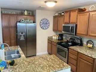 a kitchen with stainless steel appliances granite countertop a sink a refrigerator and a stove
