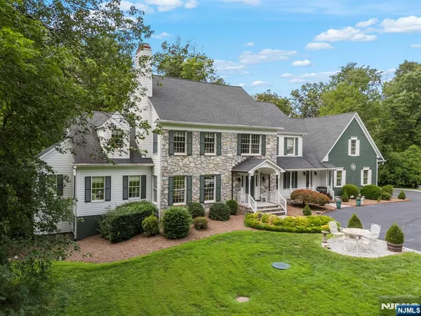 a front view of a house with garden and trees