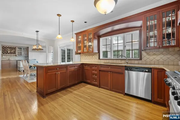 a kitchen with stainless steel appliances granite countertop a stove a sink dishwasher and a wooden cabinets