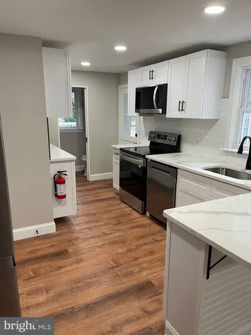 a kitchen with a sink and a stove top oven with wooden floor