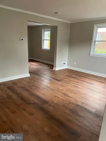 a view of an empty room with window and wooden floor